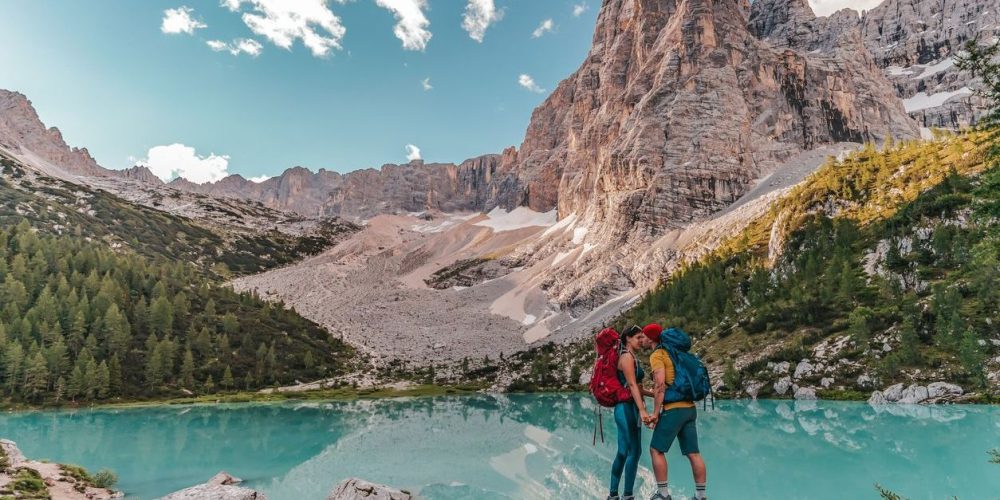 Couple hiking and kissing  in the Dolomites Italy. Beautiful Lake Sorapis Lago di Sorapis in Dolomites, popular travel destination in Italy. Blue green lake in Italian Dolomites.